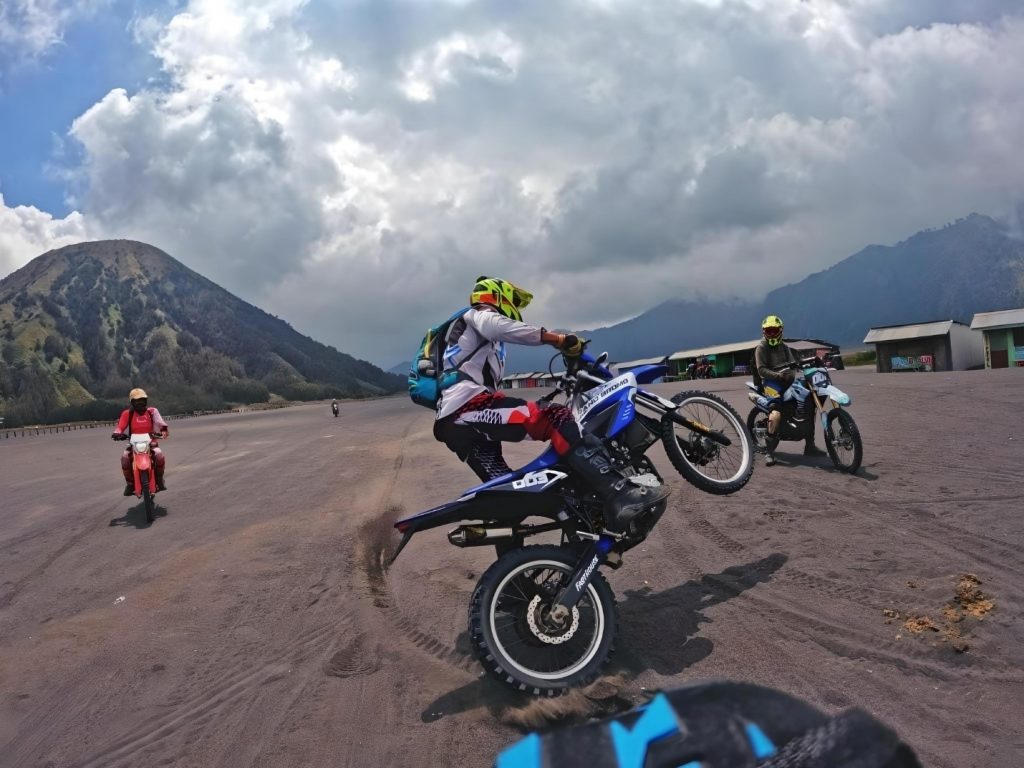 Scenic Mount Bromo landscape with a tranquil ambiance, featuring a traveler demonstrating dirt bike tricks amid the serene backdrop— creating nothing short of an amazing experience we guarantee!