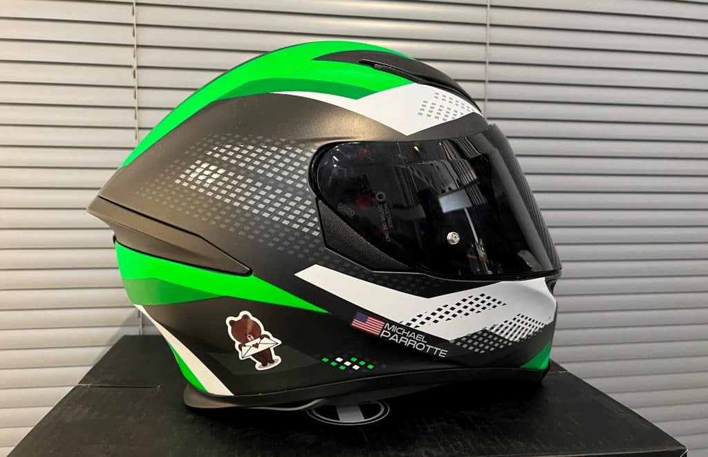 My AGV K5 helmet in Kawasaki colors – featuring a combination of classic black, high-visibility white, and vibrant green – is prominently displayed on top of its packaging box in my Maryland office. These distinct colors highlight the balance between style and safety, with white ensuring visibility and green adding a pop of vibrancy