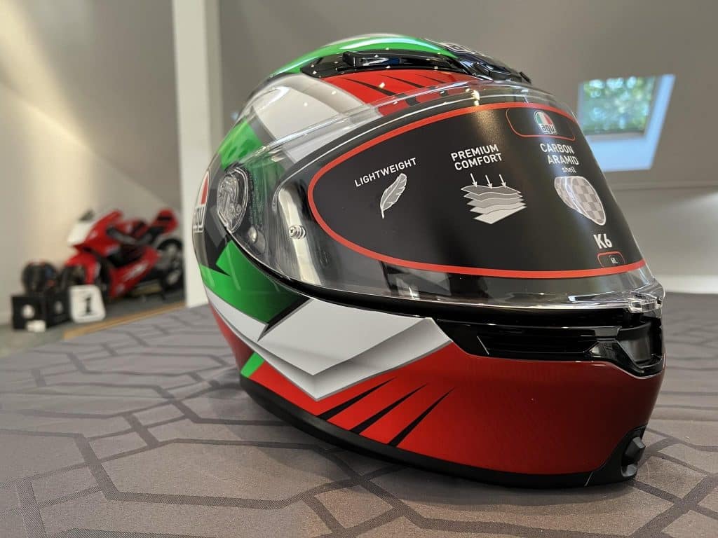 An AGV K6 S Excite Camo/Italy helmet in vibrant red, green, and white, displayed in my Maryland office. This tricolor design not only provides high visibility but also offers a statistically advantageous profile. The helmet's contoured and elegant design carries the racing heritage of professional MotoGP™ riders to the road, providing added protection and peace of mind.