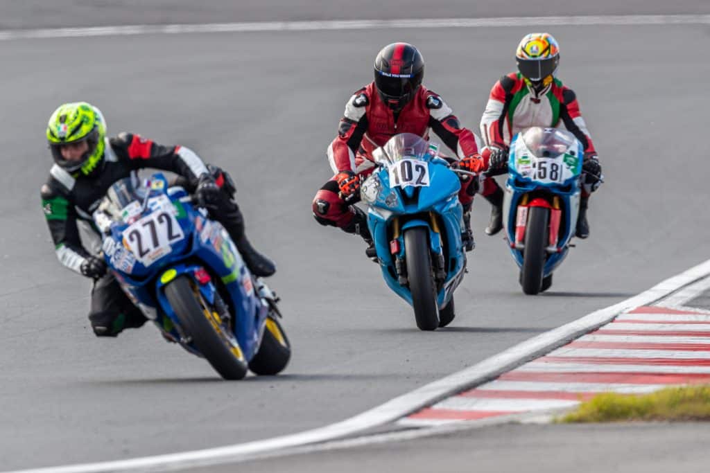 In a thrilling competition, Denis Grachev accelerates, pushing his bike to its limits as he competes against three formidable riders on the race track. His tire grips the asphalt, propelling him ahead with unmatched speed and determination.